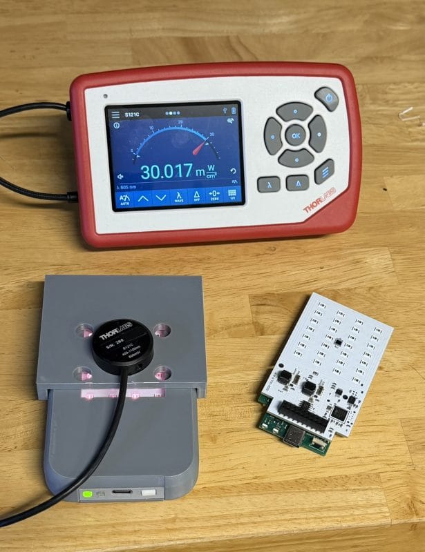 Thorlabs PM100D optical power meter displaying 30 mW/cm² at 805 nm during NIR LED calibration, with S121C sensor in calibration fixture and Rejuv production PCB